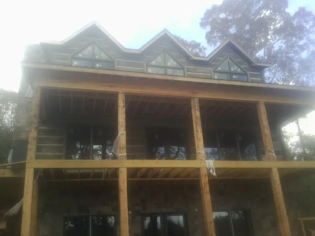 Dormers and porch framing on a large log home under construction — Roof Coating work by our crew in Holder
