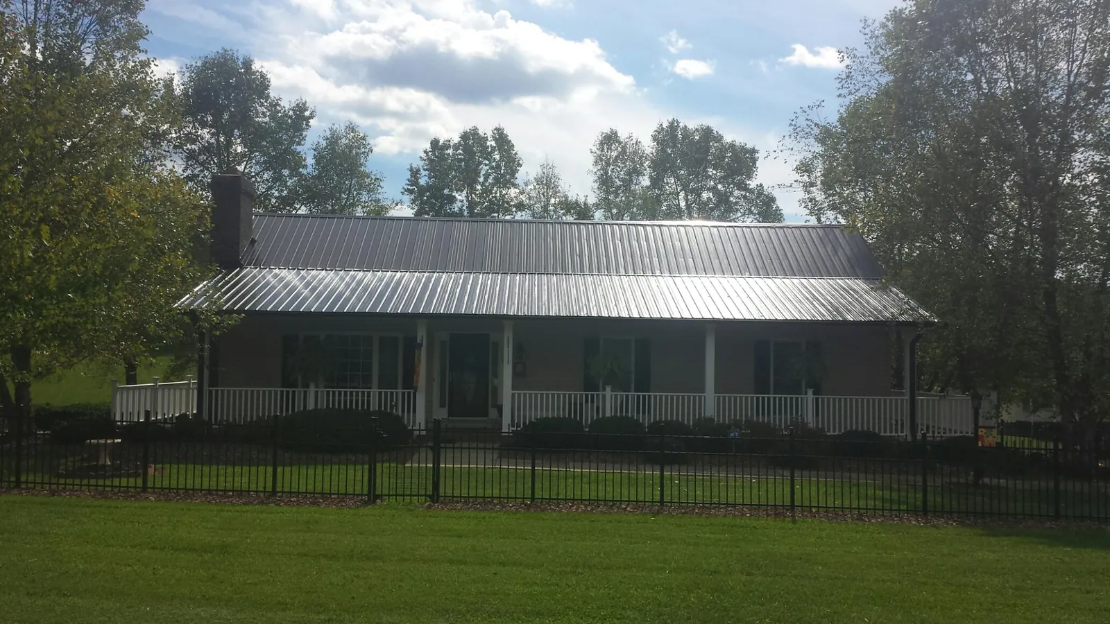 Gray metal roof on a brick ranch with a full width front porch — Gutter Guard Installation work by our crew in Holder